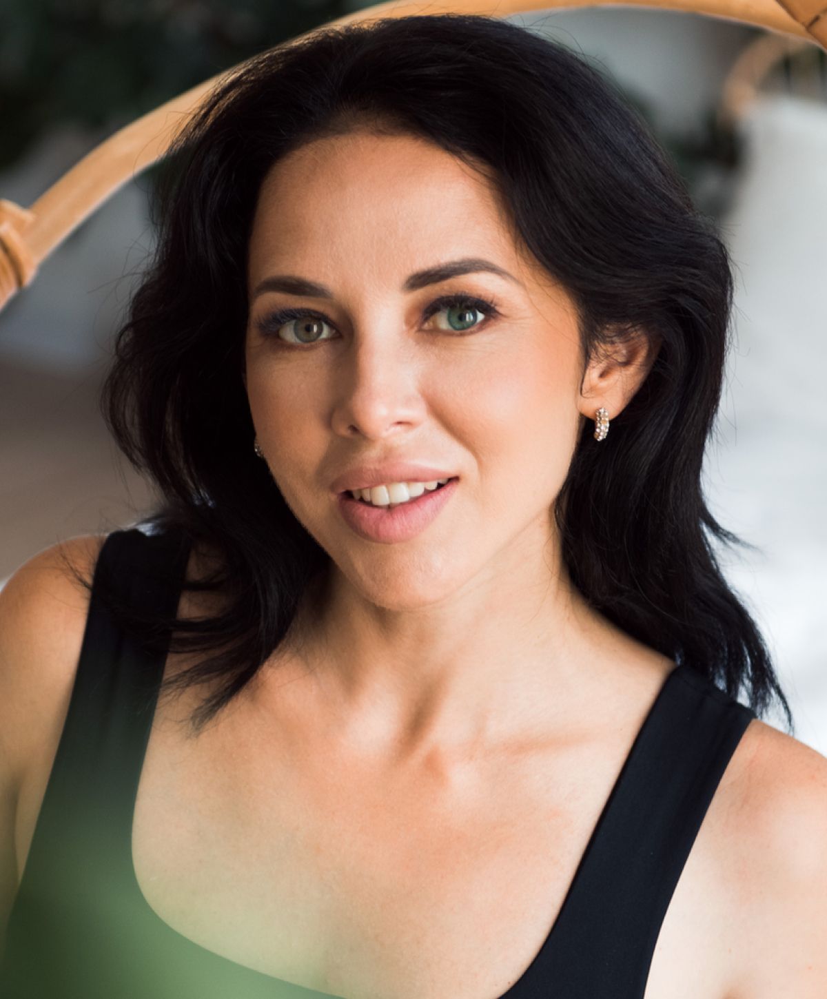 Woman smiling with dark hair and green eyes.