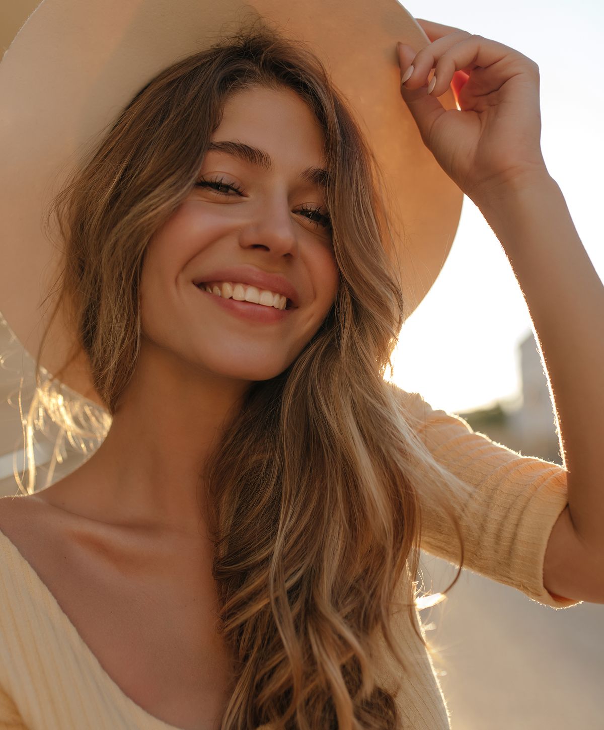 Smiling woman wearing a hat in sunlight.